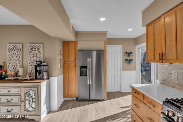 kitchen featuring light stone counters, appliances with stainless steel finishes, and light hardwood / wood-style flooring