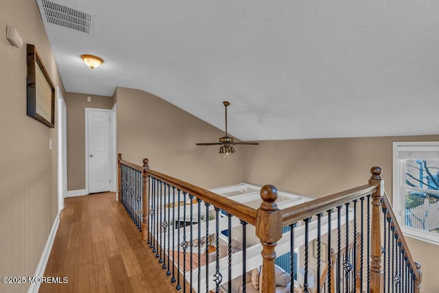 corridor featuring hardwood / wood-style flooring, lofted ceiling, and a textured ceiling