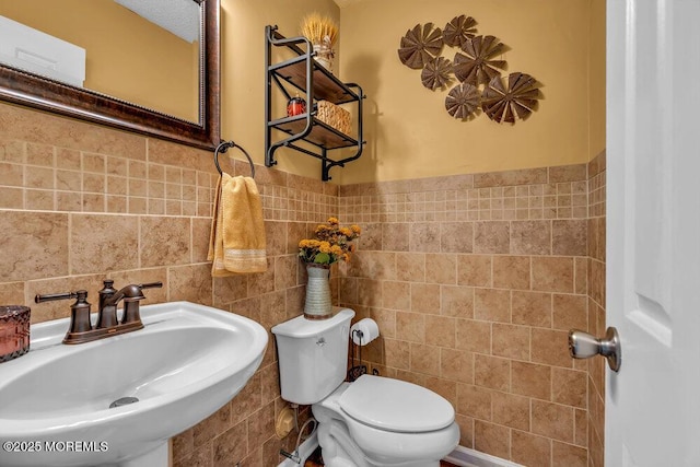 bathroom featuring sink, tile walls, and toilet