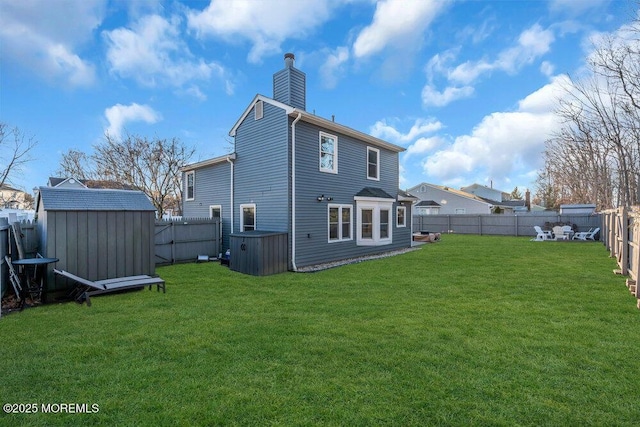 rear view of property featuring a yard and a storage unit