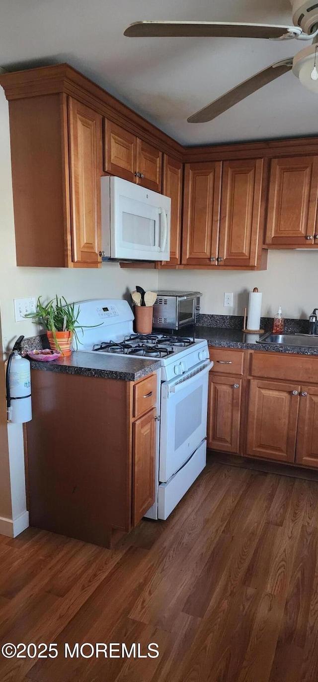 kitchen with dark hardwood / wood-style flooring, sink, white appliances, and ceiling fan