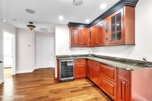 kitchen with dark stone counters, beverage cooler, and light wood-type flooring