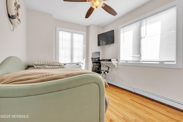 bedroom with baseboard heating, ceiling fan, and hardwood / wood-style flooring