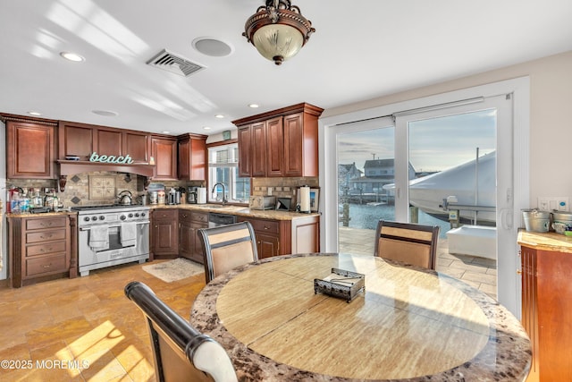 kitchen with sink, decorative backsplash, stainless steel appliances, and a water view