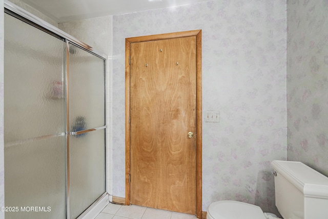 bathroom featuring wallpapered walls, a shower stall, toilet, and tile patterned floors