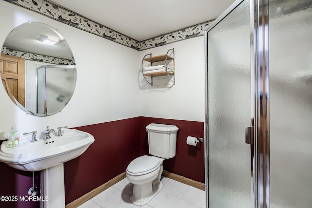 bathroom featuring a stall shower, baseboards, tile patterned flooring, and toilet