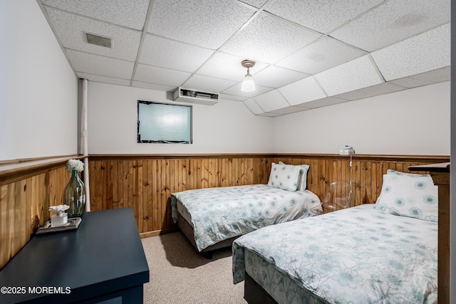 bedroom featuring a wainscoted wall, a drop ceiling, carpet flooring, and wood walls