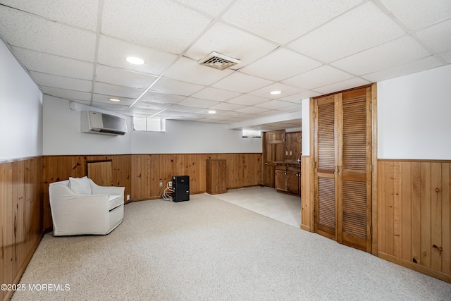 unfurnished room with a wainscoted wall, wooden walls, visible vents, and a wall mounted air conditioner