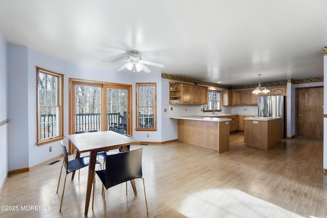 dining space featuring light wood-type flooring, baseboards, visible vents, and a ceiling fan