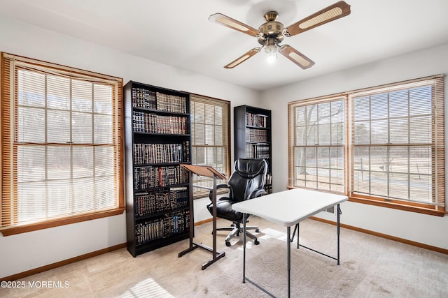 office space featuring baseboards, a ceiling fan, and light colored carpet