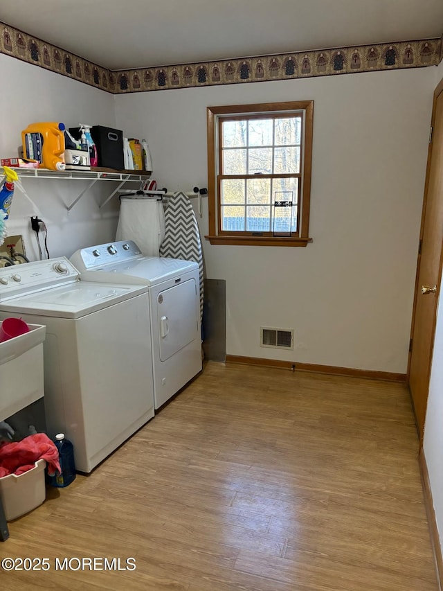 clothes washing area featuring laundry area, separate washer and dryer, visible vents, baseboards, and light wood-style floors