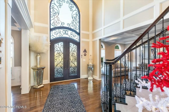 entrance foyer featuring french doors, a towering ceiling, and dark wood-type flooring