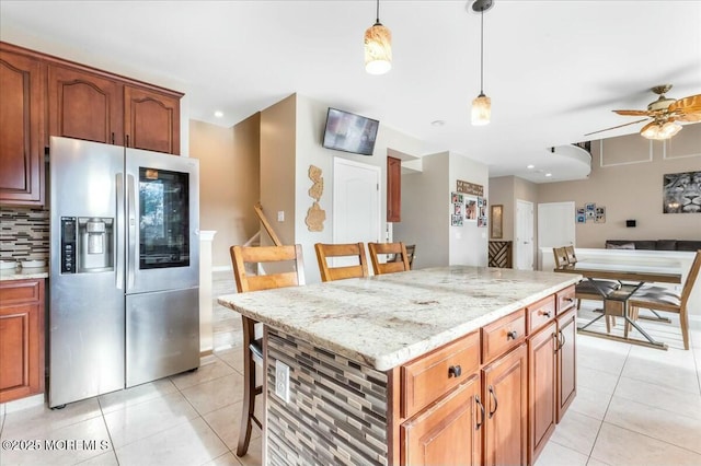 kitchen with light tile patterned floors, decorative light fixtures, stainless steel fridge, and a center island