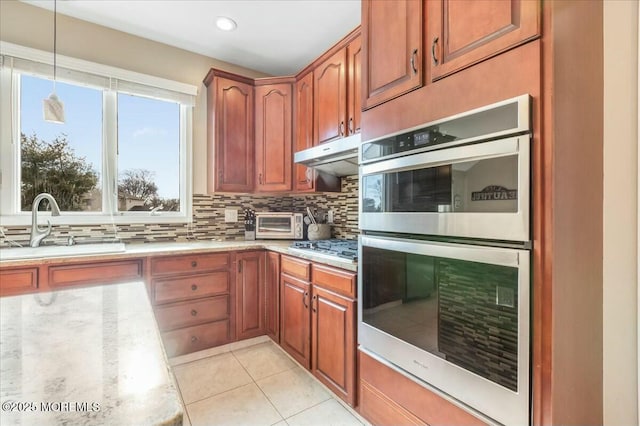 kitchen with sink, light tile patterned floors, appliances with stainless steel finishes, pendant lighting, and decorative backsplash