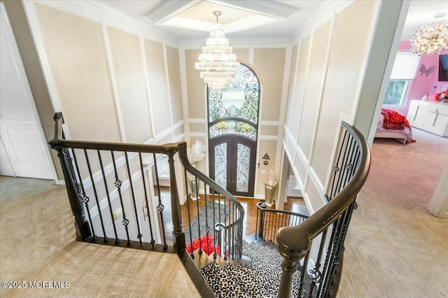 stairway featuring an inviting chandelier, carpet floors, ornamental molding, and french doors