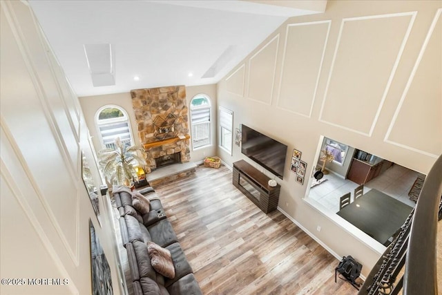 living room with a stone fireplace and light wood-type flooring