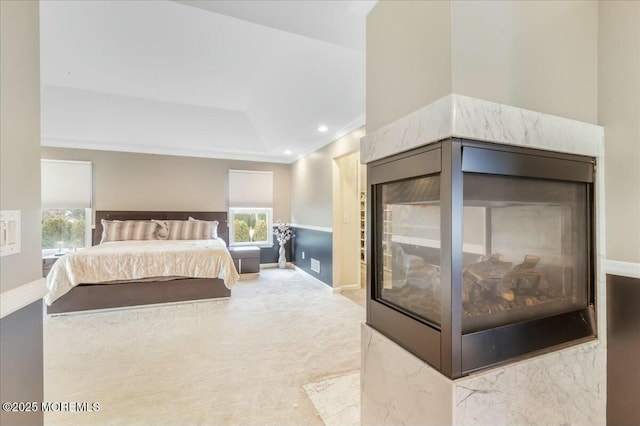 carpeted bedroom featuring a tray ceiling, crown molding, and a multi sided fireplace