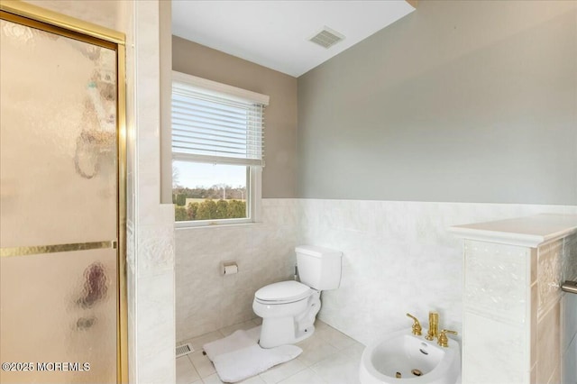 bathroom featuring tile walls, tile patterned flooring, walk in shower, toilet, and a bidet