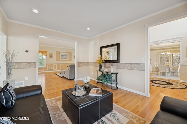 living room with crown molding, a notable chandelier, and hardwood / wood-style flooring