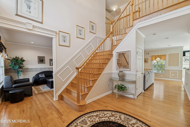 stairs with crown molding, hardwood / wood-style floors, and a high ceiling