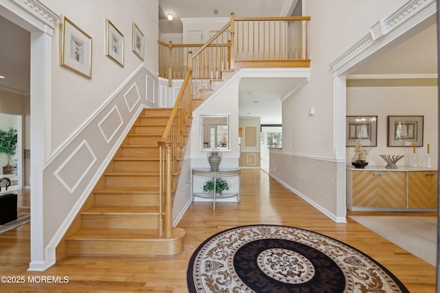 staircase featuring crown molding, hardwood / wood-style flooring, and a towering ceiling