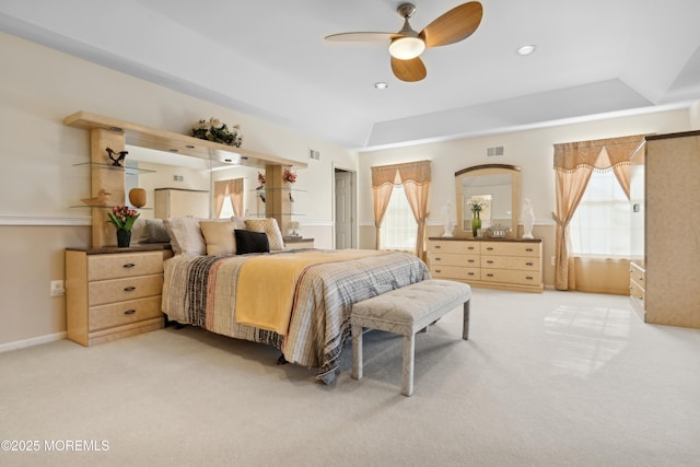 bedroom with light carpet, ceiling fan, and a tray ceiling