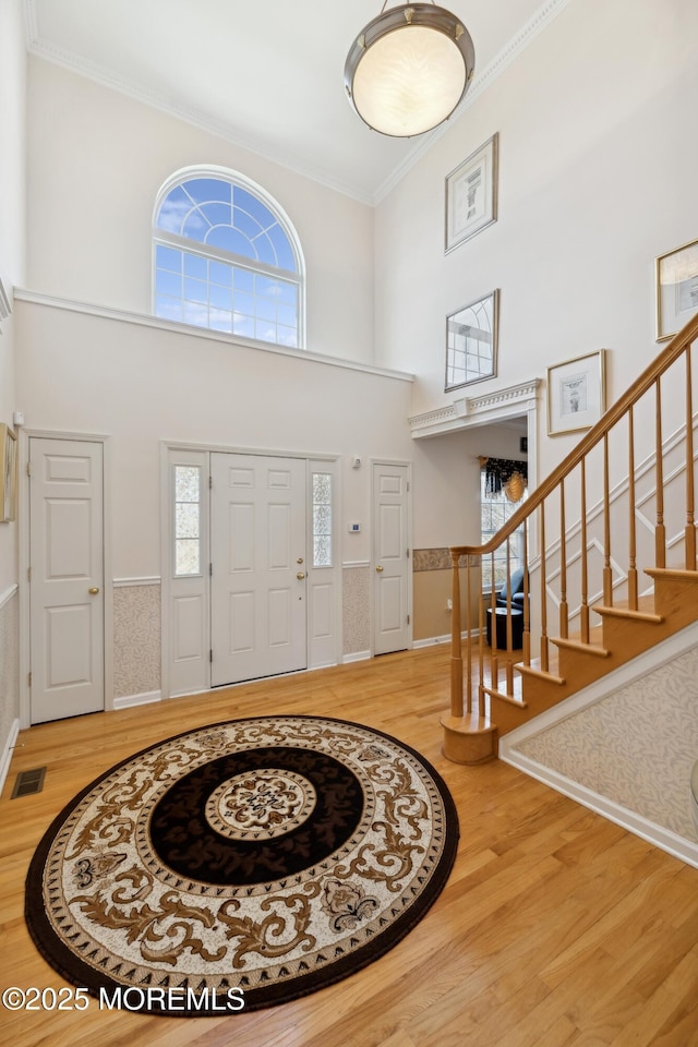 foyer with crown molding, plenty of natural light, a high ceiling, and hardwood / wood-style flooring