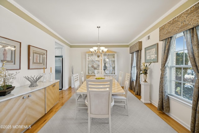 dining space with crown molding, a chandelier, and light hardwood / wood-style flooring