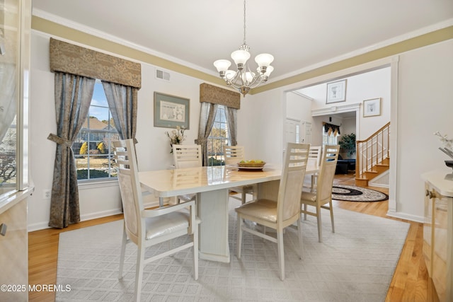 dining area featuring crown molding, light hardwood / wood-style flooring, and a chandelier