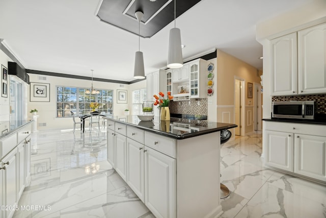 kitchen with white cabinetry, a kitchen island, pendant lighting, and crown molding