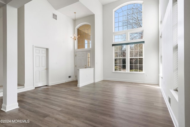 unfurnished living room with dark wood-type flooring, a high ceiling, and a notable chandelier