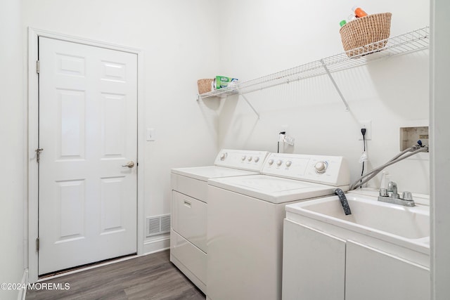 clothes washing area with hardwood / wood-style floors, washer and clothes dryer, and sink