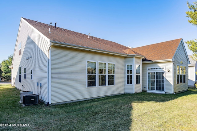 rear view of property featuring a yard and central air condition unit