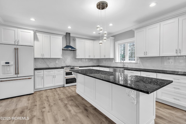 kitchen with sink, white cabinetry, dark stone countertops, high quality appliances, and wall chimney exhaust hood