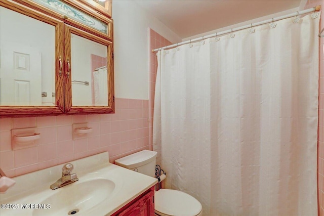 bathroom with vanity, toilet, and tile walls