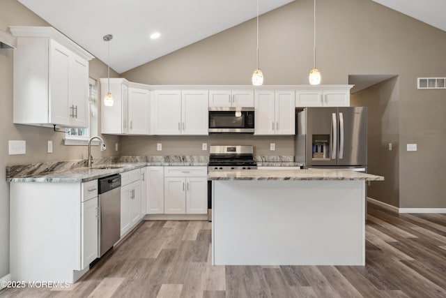 kitchen with appliances with stainless steel finishes, a kitchen island, sink, and white cabinets