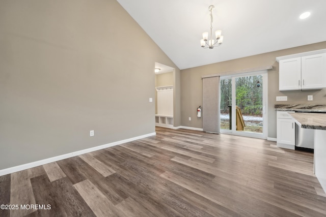 unfurnished dining area with high vaulted ceiling, light wood-type flooring, and a chandelier