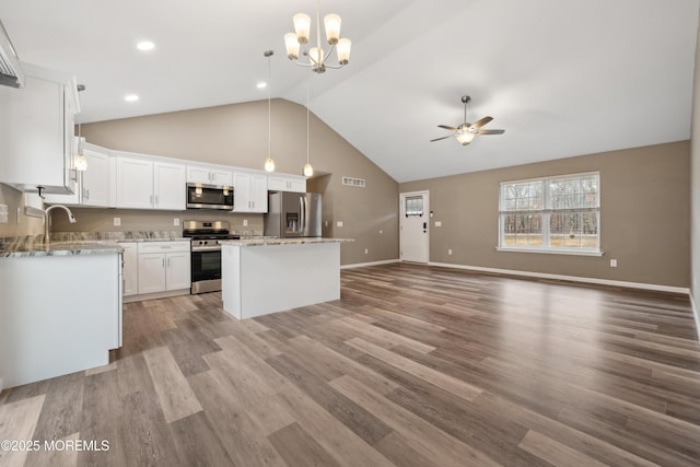 kitchen featuring white cabinetry, appliances with stainless steel finishes, a center island, and decorative light fixtures