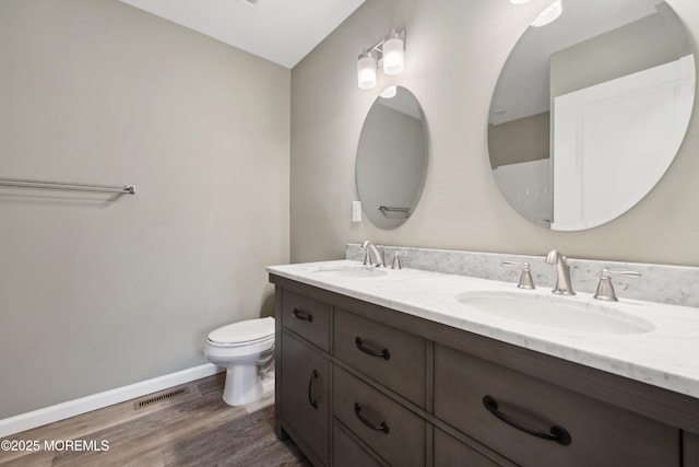 bathroom with wood-type flooring, vanity, and toilet