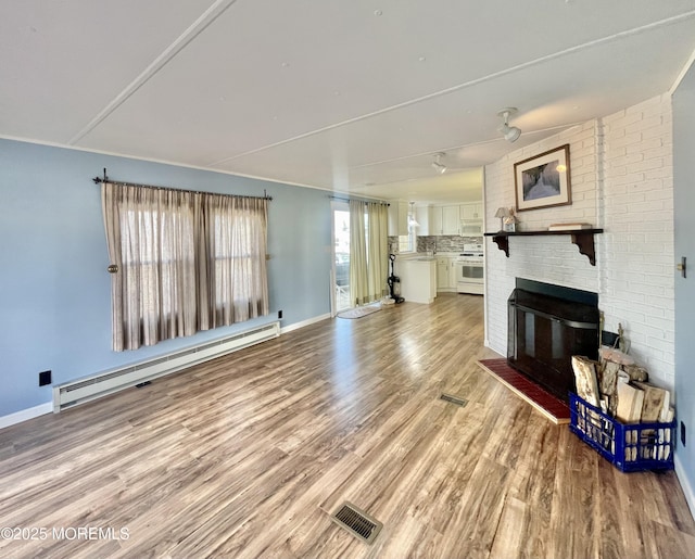 unfurnished living room featuring a brick fireplace, light hardwood / wood-style flooring, and a baseboard heating unit