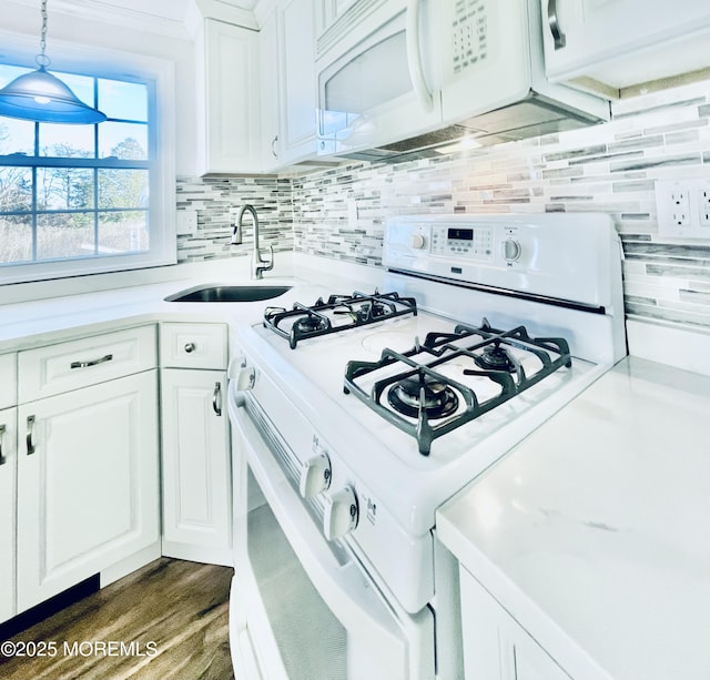 kitchen with hanging light fixtures, white appliances, sink, and white cabinets