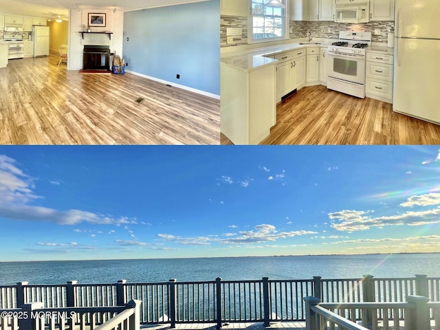 kitchen featuring a water view, white cabinetry, tasteful backsplash, light wood-type flooring, and white appliances