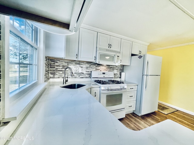 kitchen featuring sink, white cabinetry, hardwood / wood-style flooring, white appliances, and backsplash