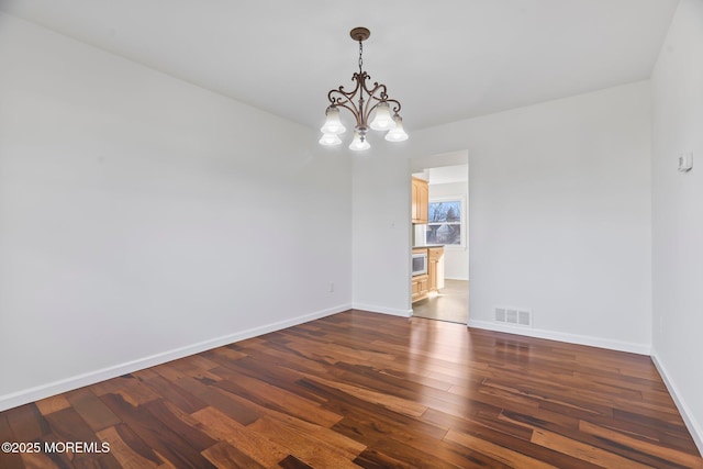 unfurnished room with an inviting chandelier and dark wood-type flooring