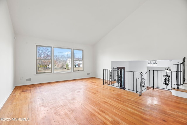 unfurnished room featuring wood-type flooring and high vaulted ceiling