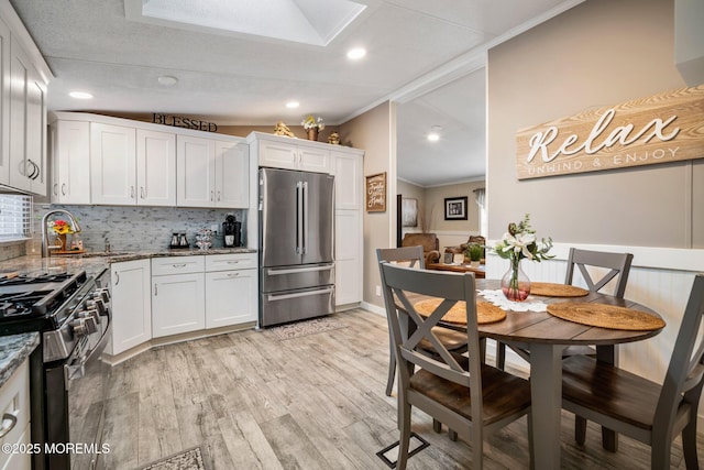 kitchen featuring sink, stone counters, white cabinetry, gas range oven, and high end refrigerator