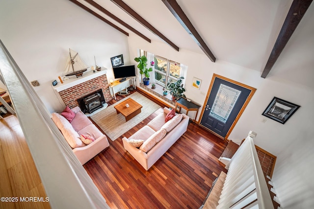 living room featuring dark hardwood / wood-style flooring, a brick fireplace, and beamed ceiling