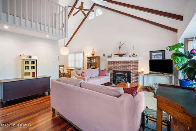 living room featuring wood-type flooring, beam ceiling, high vaulted ceiling, and a brick fireplace