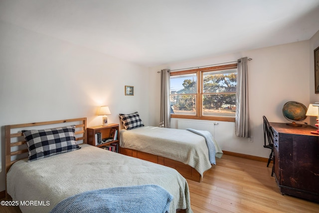 bedroom featuring radiator and light hardwood / wood-style floors