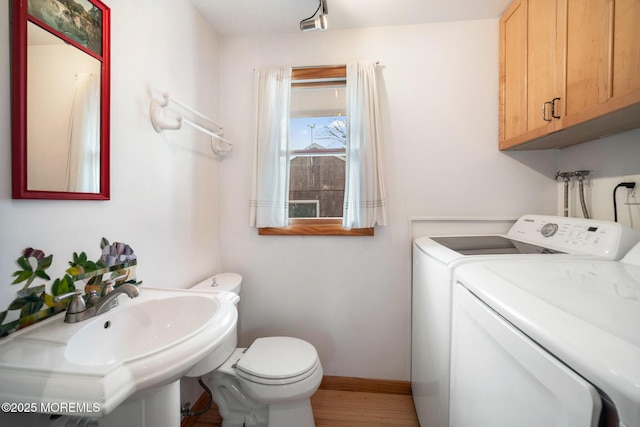 bathroom featuring sink, washer and clothes dryer, hardwood / wood-style floors, and toilet